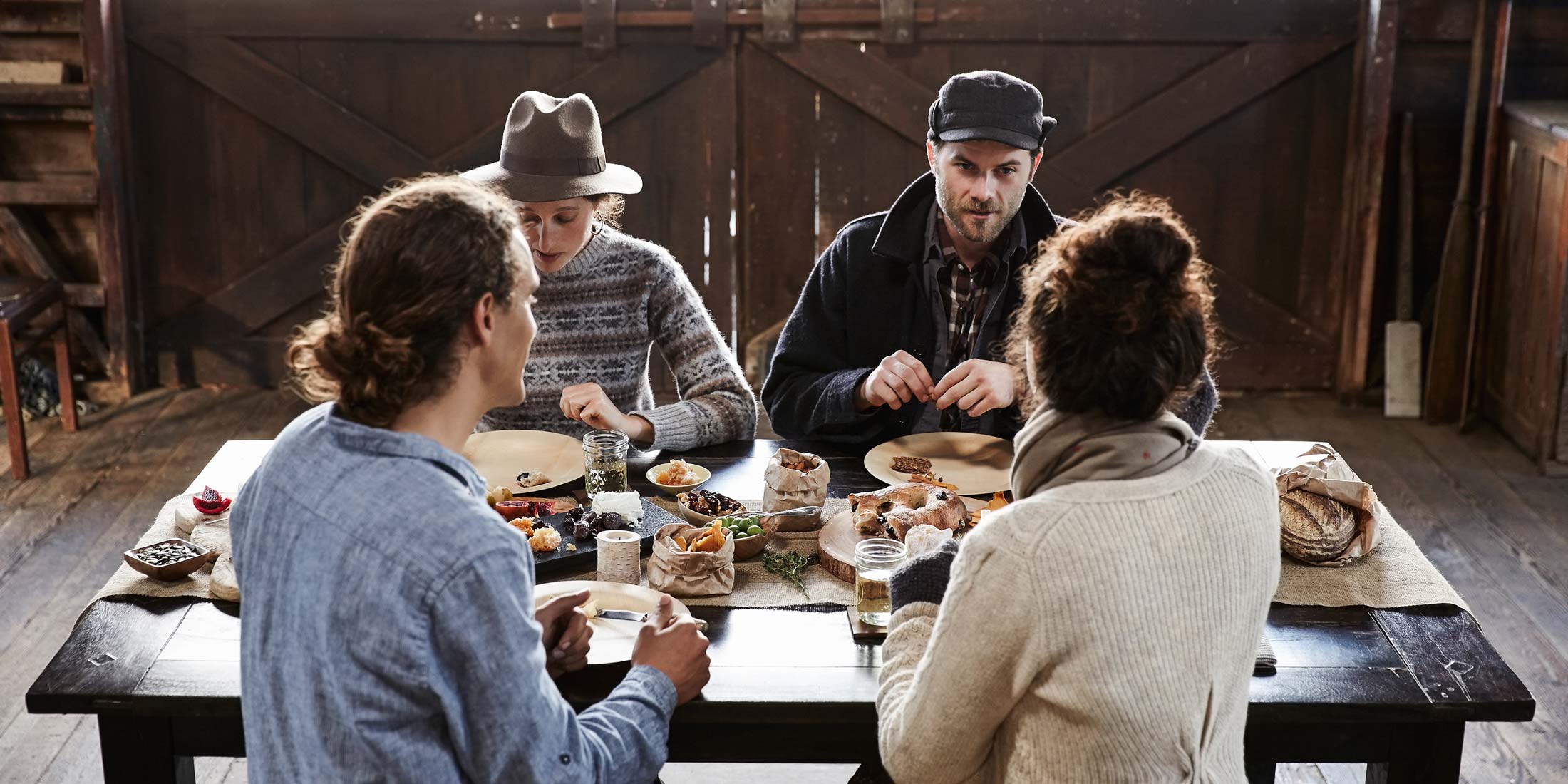 Gruppe junger Menschen beim Essen in rustikaler Umgebung
